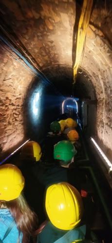 Powiększ zdjęcie: Grupa dzieci płynie łodzią w górniczym korytarzu