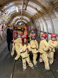 Powiększ zdjęcie: Grupa dzieci pozuje do zdjęcia przed kolejką górniczą Karlik