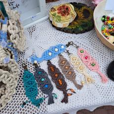 Powiększ zdjęcie: Kolorowe rękodzieło seniorów zaprezentowane na stoisku. Makramowe breloczki do kluczy.