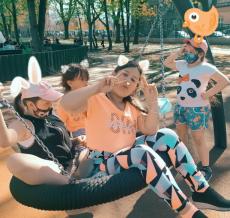 Powiększ zdjęcie: Plac zabaw. Zdjęcie przedstawia trzy dziewczynki, które huśtają się na huśtawce wykonanej z opony. Obok stoi czwarta dziewczynka, która im się przygląda. 