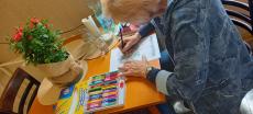 Powiększ zdjęcie: Seniorka z Klubu Seniora w Komorowicach podczas malowania kolorowanek relaksacyjnych