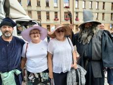 Powiększ zdjęcie: Seniorki w kapeluszach wraz z Seniorami przebranymi w stroje z średniowiecznych czasów podczas Parady Kapeluszy