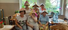 Powiększ zdjęcie: Seniorki z Klubu Seniora w Komorowicach w papierowych kapeluszach na głowie które własnoręcznie wykonały