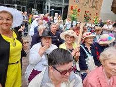 Powiększ zdjęcie: Seniorki z Komorowic w strojnych nakryciach głowy siedzą na widowni podczas koncertu przy BCK
