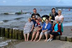 Powiększ zdjęcie: Seniorzy z OWOS siedzą na falochronach na plaży w Niechorzu