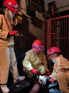 Powiększ zdjęcie: Troje dzieci w sztygarskich ubraniach roboczych wykonuje prace górnicze