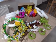 Powiększ zdjęcie: Wianek Wielkanocny. Box zawiera – kolka styropianowe, len, gałązki bazi, kwiatki z bibuły, piórka, jajeczka, motyle, ptaszki, kokardki, klej. 