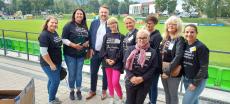 Powiększ zdjęcie: Zdjęcie przedstawia 8 kobiet i Prezydenta miasta Bielska-Białej na tle zielonej murawy boiska