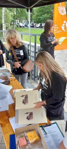 Powiększ zdjęcie: Zdjęcie przedstawia dwie kobiety zajęte pracą przy dokumentacji Pikniku