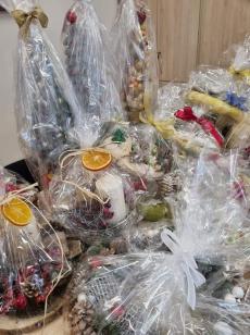 Powiększ zdjęcie: Zdjęcie przedstawia kilka prezentów zapakowanych w przezroczysta folię, zawiązanych ozdobnymi wstążkami i udekorowanymi suszonymi plastrami pomarańczy.