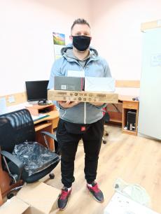 Powiększ zdjęcie: Zdjęcie Przedstawia Pana pełniącego funkcję rodziny zastępczej, który trzyma w rękach otrzymany w ramach projektu zestaw komputerowy.