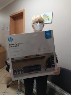 Powiększ zdjęcie: Zdjęcie przedstawia Panią pełniącą funkcję rodziny zastępczej, która trzyma w rękach otrzymane w ramach projektu urządzenie wielofunkcyjne.