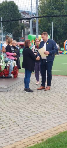 Powiększ zdjęcie: Zdjęcie przedstawia Prezydenta miasta Bielska-Białej wręczającego list gratulacyjny kobiecie, która pełni funkcję rodzinnego domu dziecka