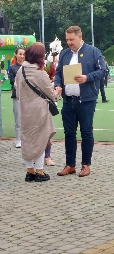 Powiększ zdjęcie: Zdjęcie przedstawia Prezydenta miasta Bielska-Białej wręczającego list gratulacyjny kobiecie, która pełni funkcję rodziny zastępczej zawodowej