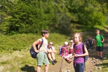 Grupa dzieci wraz z opiekunem odpoczywa w drodze na górę Magurka