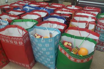 Paczki świąteczne wypełnione owocami, słodyczami i artykułami żywnościowymi.