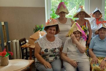 Seniorki z Klubu Seniora w Komorowicach w papierowych kapeluszach na głowie które własnoręcznie wykonały