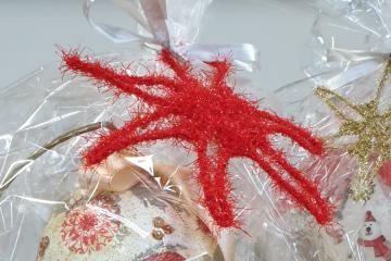 Zdjęcie przedstawia bombkę świąteczną zapakowaną w folię z czerwona gwiazdą