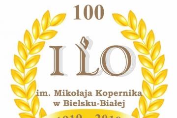 Zdjęcie przedstawia logo I Liceum Ogólnokształcącego im. Kopernika w Bielsku-Białej zawierające dwie złote gałązki laurowe połączone wstęgą i datami od 1919 do 2019
