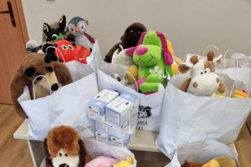 Zdjęcie przedstawia mnóstwo kolorowych maskotek i 5 pudełek maseczek ochronnych