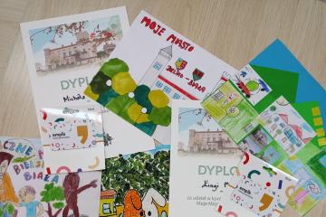 Zdjęcie przedstawia rozłożone na biurku prace plastyczne.